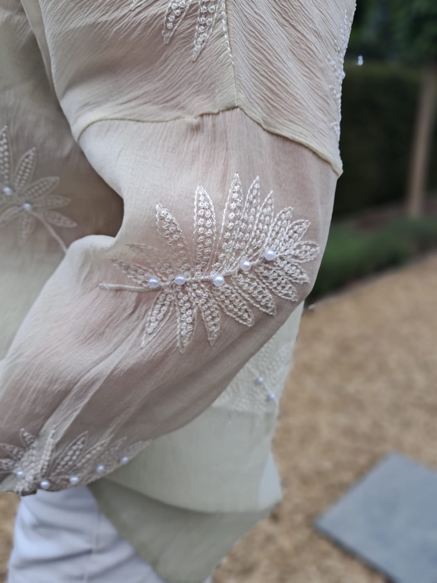 Lichtgroene, transparante blouse met geborduurde bladmotieven, afgewerkt met pareltjes