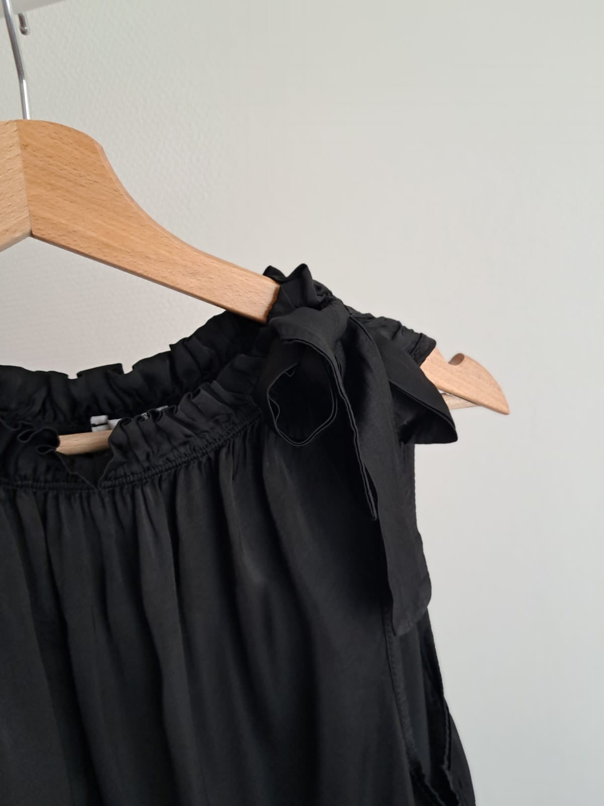 Zwart, elegant, mouwloos blousje met frons aan de hals en afgewerkt met lint ad hals
