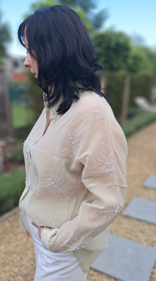 Lichtgroene, transparante blouse met geborduurde bladmotieven, afgewerkt met pareltjes