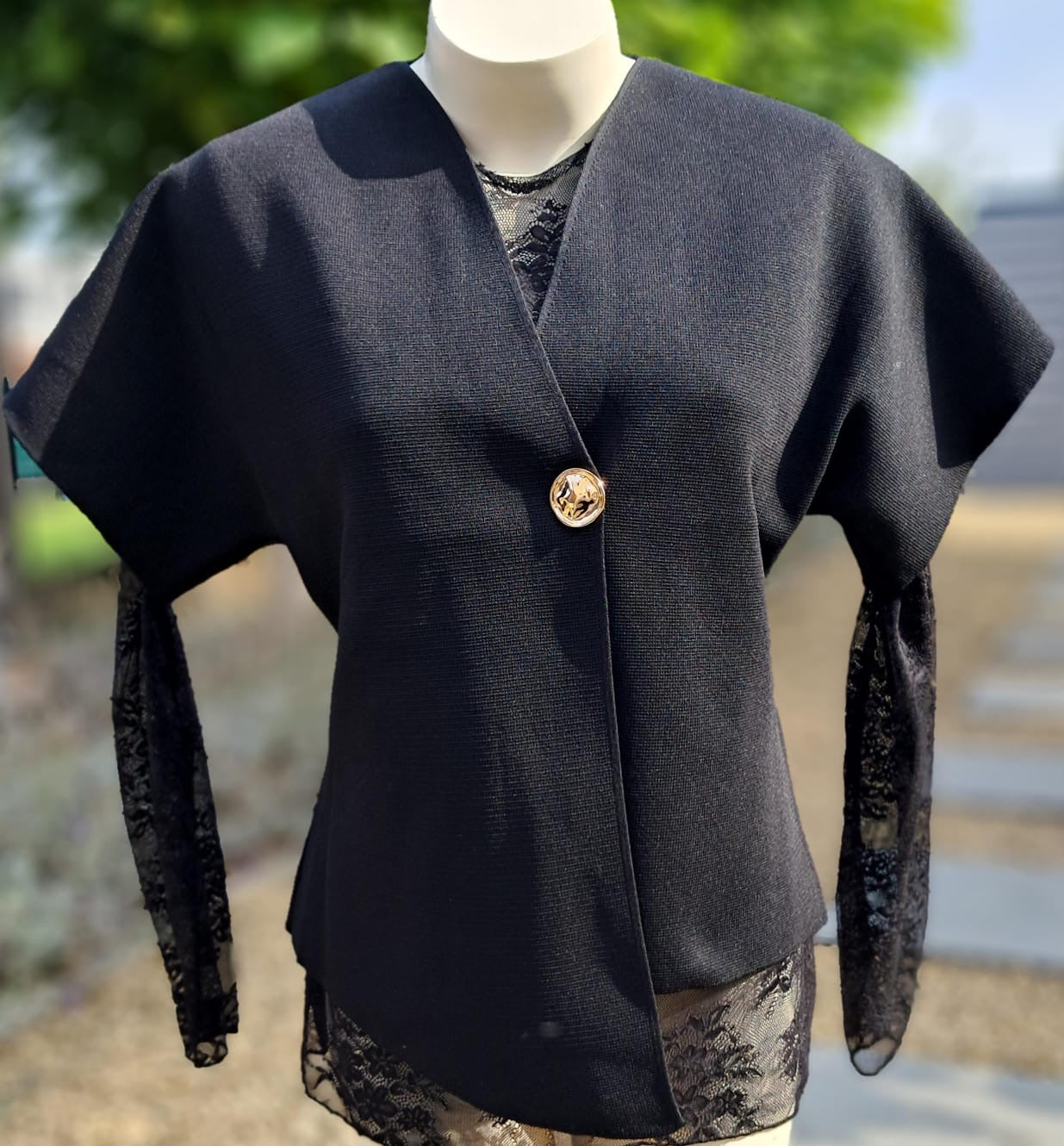 Mouwloze, asymmetrische gilet met gouden knoop