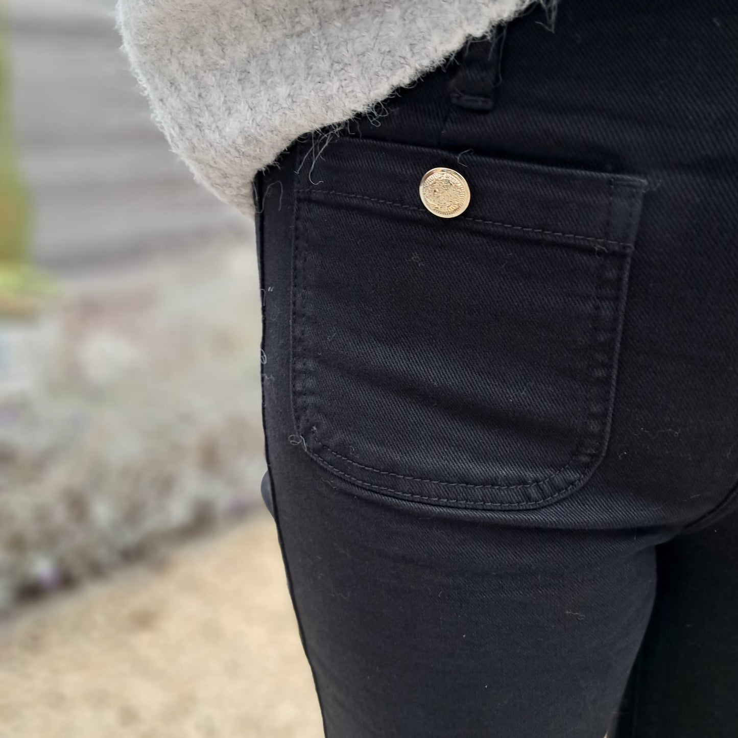 Zwarte jeans met gouden knoop vooraan op de zakken